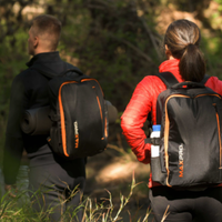 Two people hiking with a MAXPRO backpacks in a forest setting
