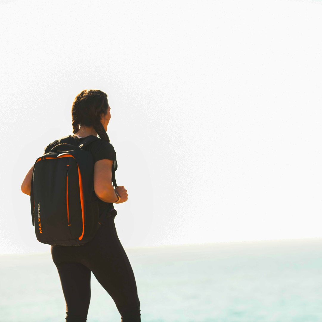 Person with a black and orange MAXPRO backpack standing against a light background