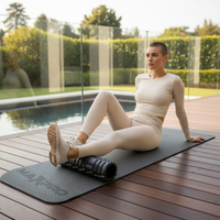 woman using foam roller to roll out her calf outside next to a pool
