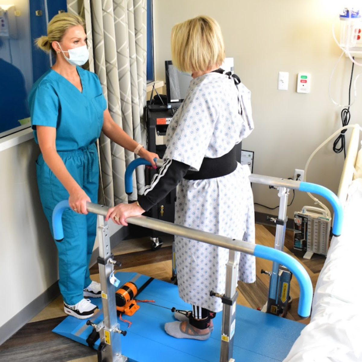 Physiotherapist assisting a patient using a walker in a hospital setting