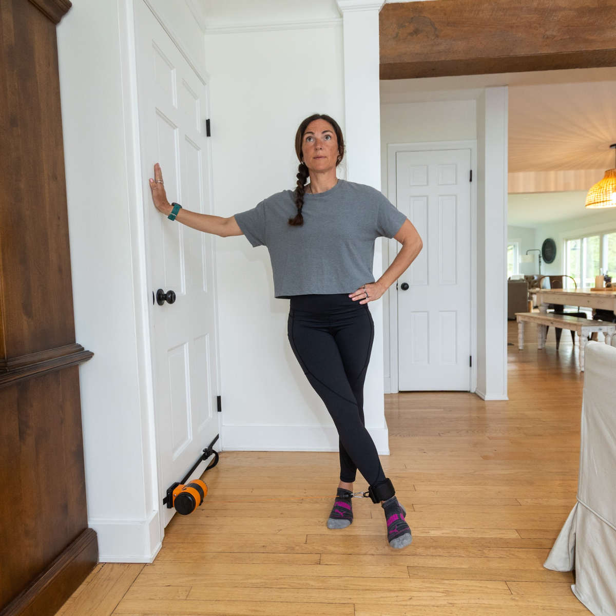 Woman standing in a room with wooden floors and white walls