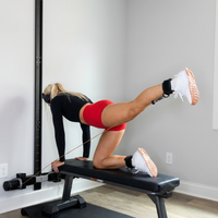 Person exercising on a bench with the MAXPRO mounted in the slim line wall track. She is wearing the ankel strap and doing a kick back exercise.