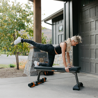Woman exercising on a bench outside a house