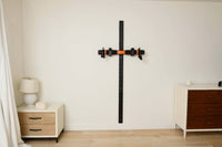 Orange MAXPRO cable trainer mounted on a black SlimLine Wall Track between a bedside table and dresser in a bedroom.⠋