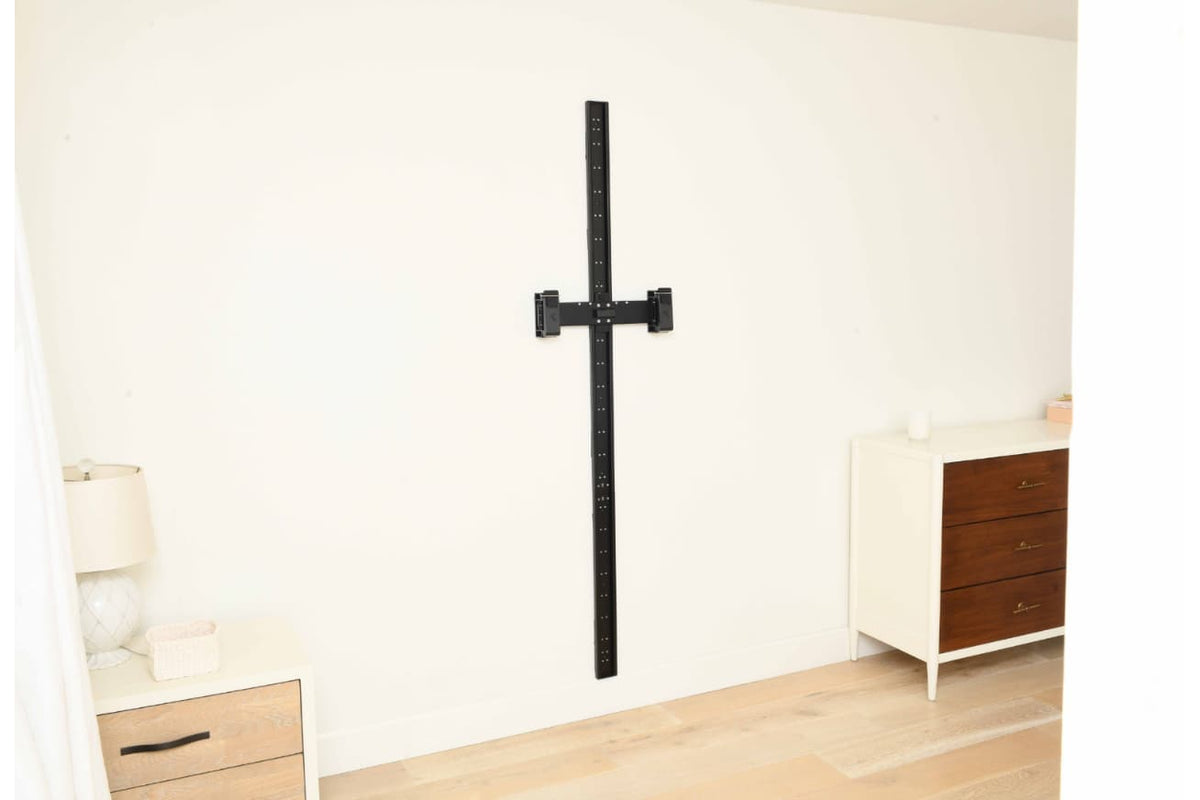 Black MAXPRO SlimLine Wall Track with adjustable mounting crossbar installed vertically on a white bedroom wall.